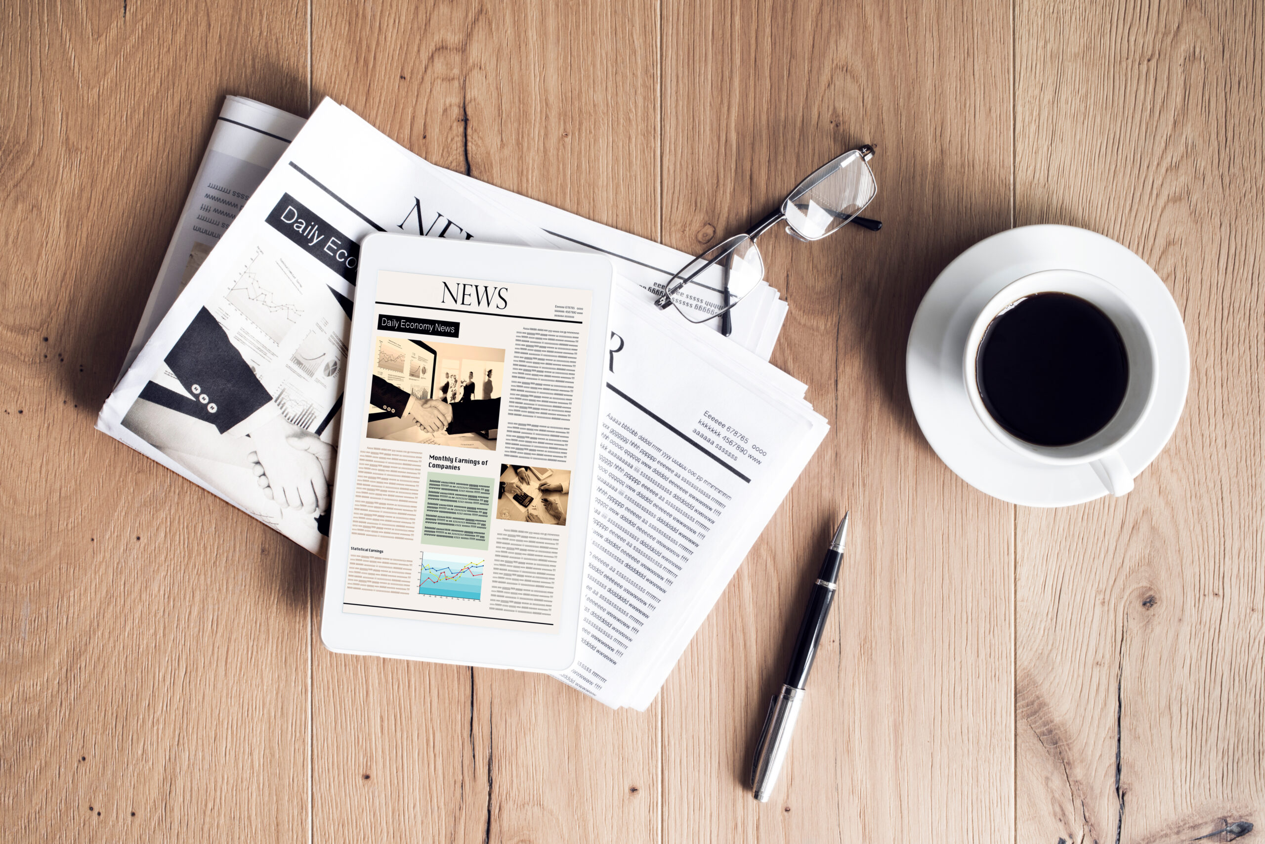 Newspaper with tablet on wooden table